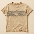 Sand-coloured t-shirt with a floral band and cartoon shark across the chest — flat lay