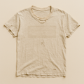 Pale oatmeal t-shirt with no print left, only a faint rectangular ghost on the chest — flat lay